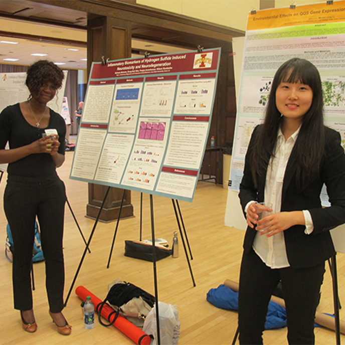 Two female honors students presenting their research at the poster session.