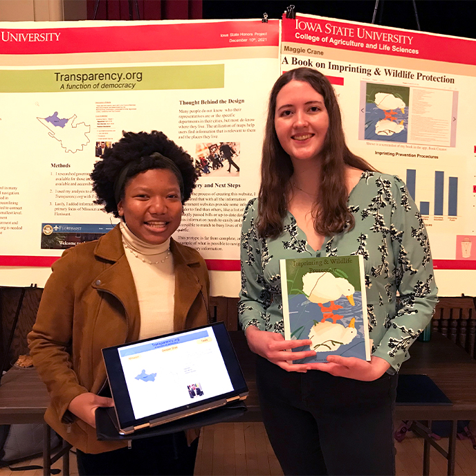Two female honors students presenting their research at the Fall 2021 poster session.