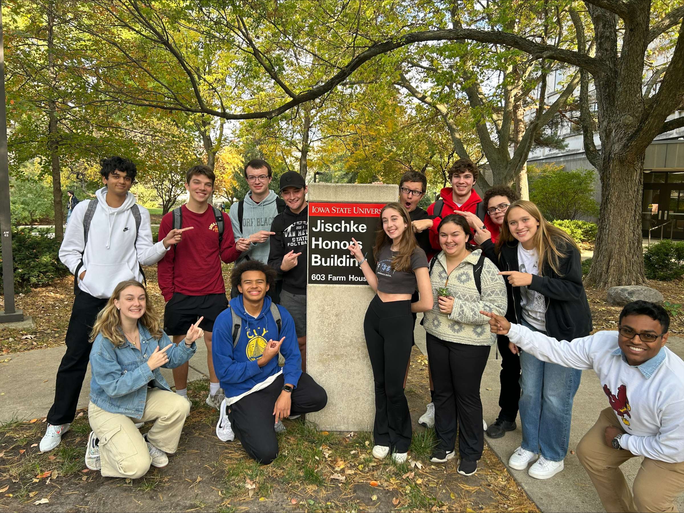 Honors 121 class posing in front of the Jischke Honors Building sign.