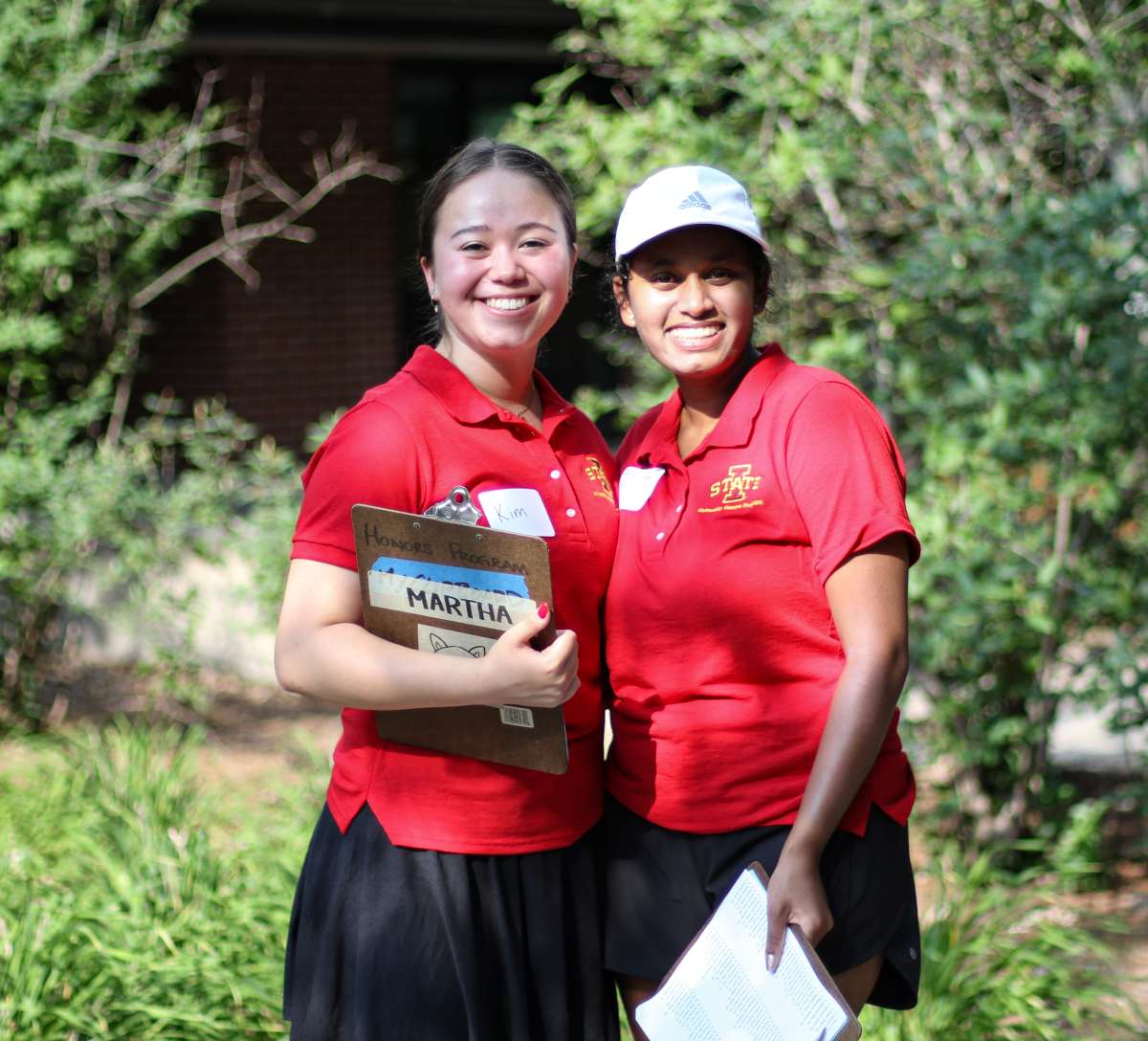 Two female honors student ambassadors in red ISU Honors Program polo shirts.